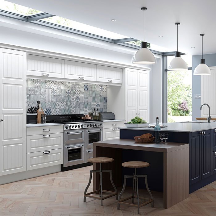 Grooved panel kitchen. White wall and base units. Tall units with 4 panel doors. Kitchen island in dark blue with cupboards, drawers and seating