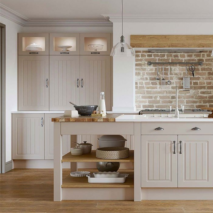 Newport grooved raised panel kitchen in cashmere beige. Tall wall units with glass inserts at the top and a kitchen island with cupboards, drawers and open shelving