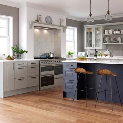 Chatham raised panel kitchen. Light Grey base units and wall units with glass inserts. Marine Blue kitchen island with drawers and seating