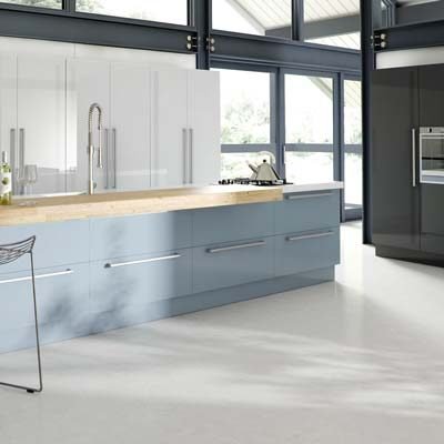 Phoenix Acrylic Ultra-Gloss Detailed Door Edge Kitchen. Ultra Modern Style in 3 different colours. One wall in full height units in White, Another wall of tall units with built in oven in Anthracite and a long narrow kitchen island with Deep drawers in Denim with overhanging worktop for seating